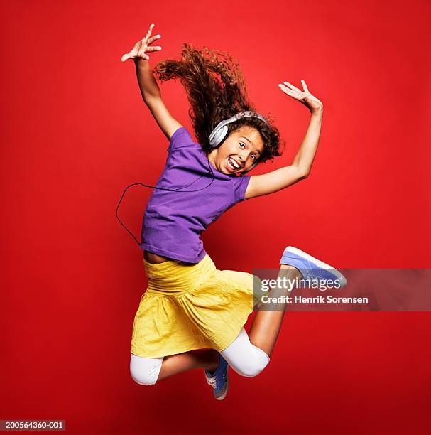 girl (12-13) wearing headphones and jumping, smiling, portrait - 12 13 anos - fotografias e filmes do acervo