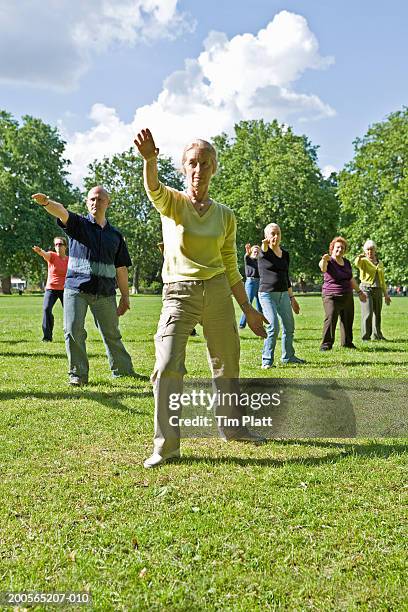 group of people practicing tai chi in park, matur elady in foreground - practising tai-chi stock pictures, royalty-free photos & images