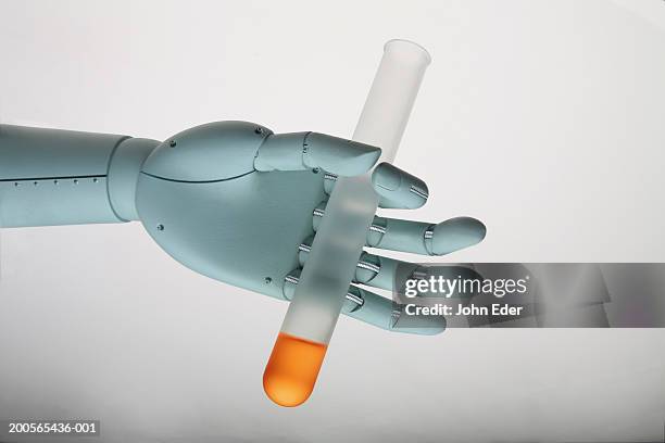 robotic hand holding test tube filled with liquid (digital composite) - compuesto digital fotografías e imágenes de stock