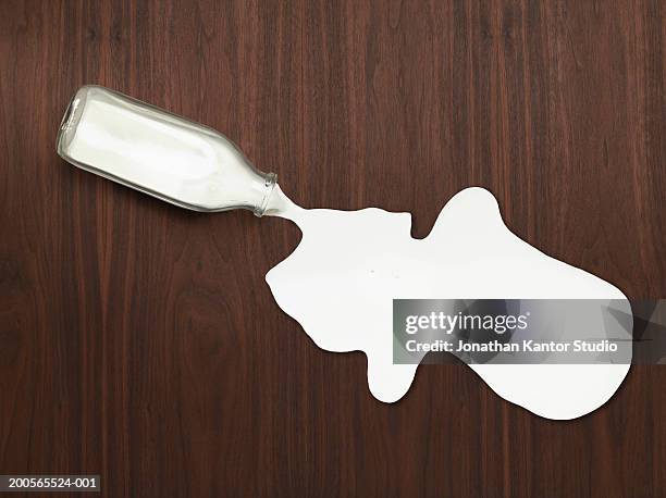 bottle of spilled milk on wood, overhead view - spilt milk stock-fotos und bilder