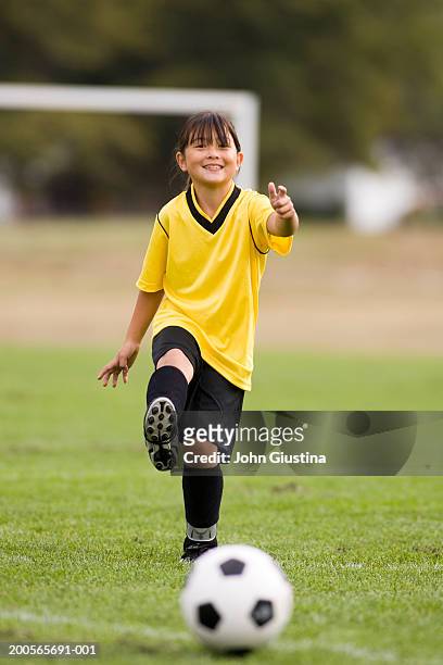 girl (8-9) kicking football, smiling - young girl soccer stock pictures, royalty-free photos & images