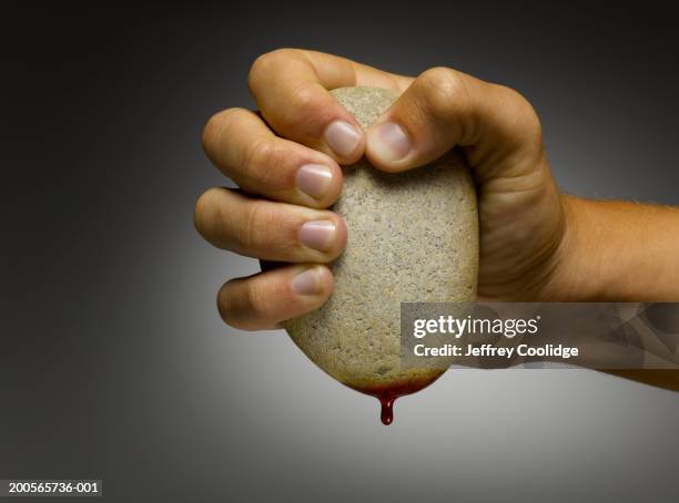 man squeezing blood from stone - stone hand stock pictures, royalty-free photos & images