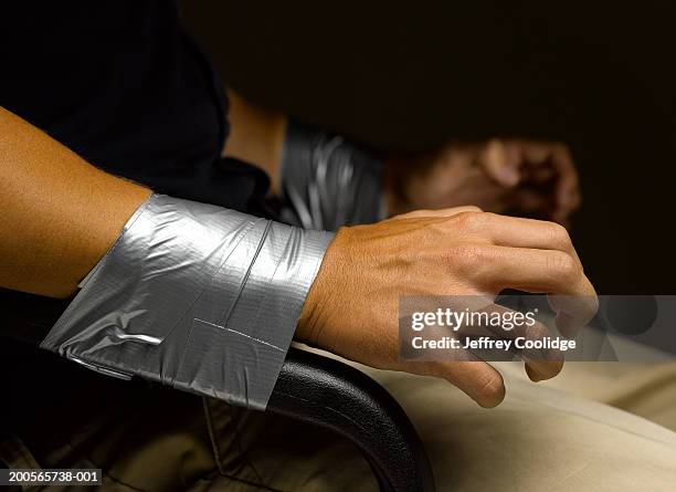 man's wrists taped to arms of chair, close-up - amarrado fotografías e imágenes de stock