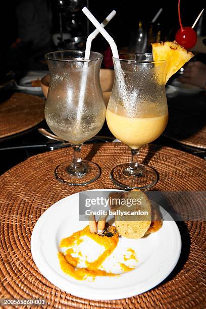 extinguished cigarette on plate of food by empty pina coladas - pina colada stock-fotos und bilder