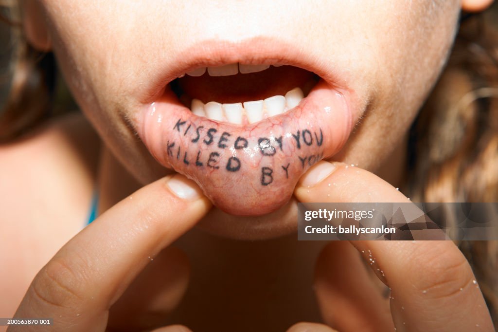 Kissed by you, killed by you tattooed on inside of woman's lip