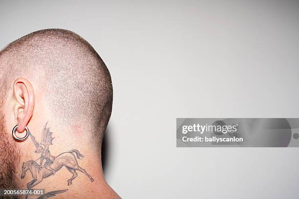 man with neck tattoo, shaved head and earrings, against white background - earring stud stock pictures, royalty-free photos & images