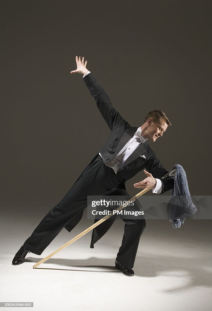 Man in tuxedo dancing with mop