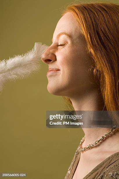 young woman with nose being tickled by feather, profile - kietelen stockfoto's en -beelden