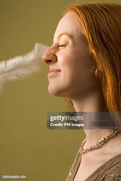 young woman with nose being tickled by feather, profile - tickling - fotografias e filmes do acervo