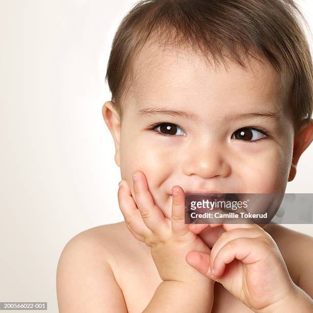 baby boy (12-15 months) putting finger in mouth, close-up, portrait - kid putting finger in mouth stock-fotos und bilder
