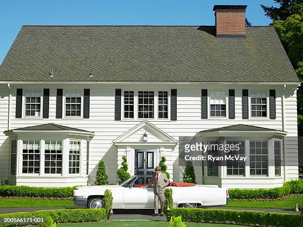 senior man standing by convertible car outside house - car interieur stock-fotos und bilder