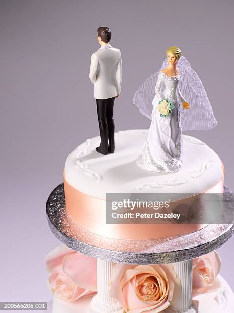 bride and groom figurine standing back to back on wedding cake - wedding cake figurine stock pictures, royalty-free photos & images