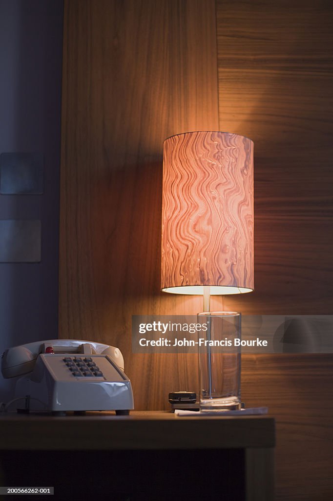 Telephone and illuminated lamp on bedside table