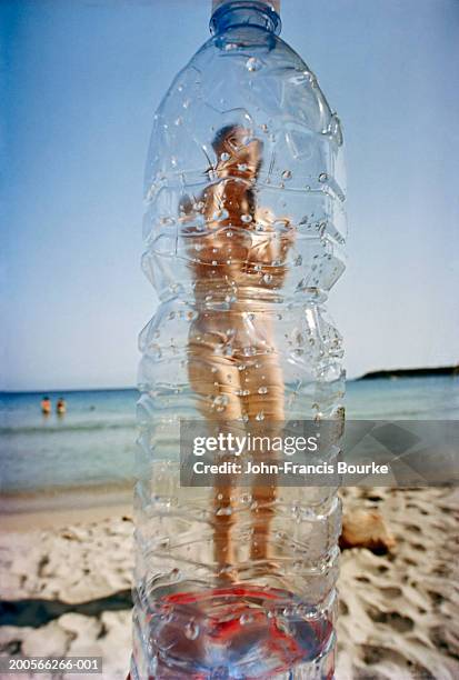 woman on beach, photographed through plastic bottle - see through swimsuit ストックフォトと画像