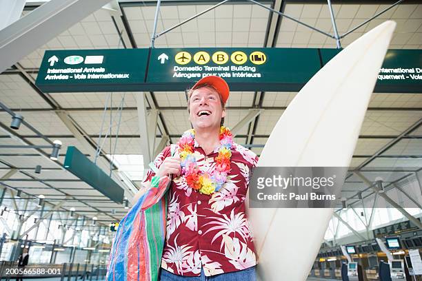 man carrying surfboard in airport, smiling - premiere of comedy dynamics the fury of the fist and the golden fleece arrivals stockfoto's en -beelden