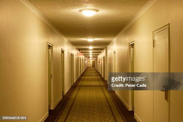 view down hotel corridor with illuminated lamps on ceiling - hotel tür stock-fotos und bilder