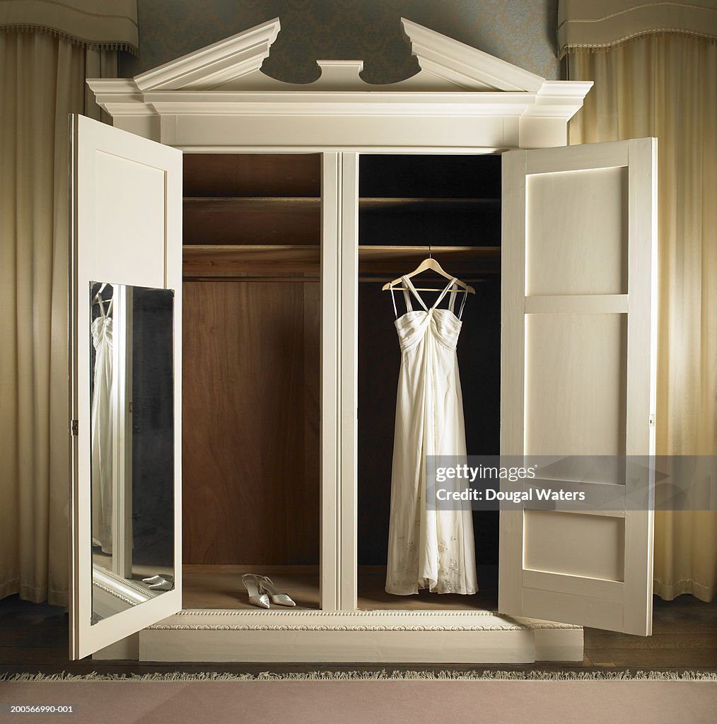 Wedding dress hanging in wardrobe with shoes