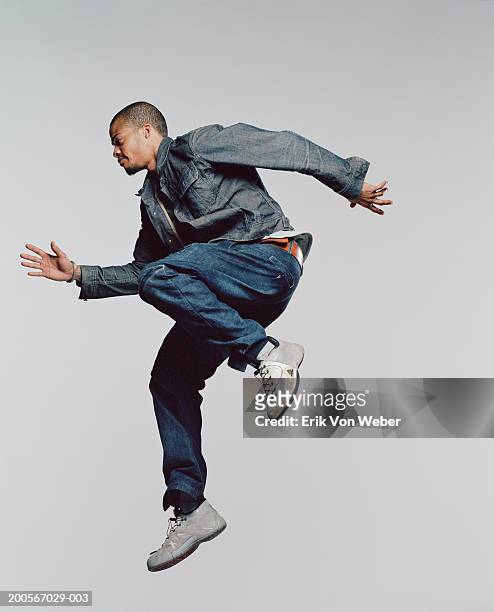 young man jumping in mid-air, side view - gray jeans stockfoto's en -beelden
