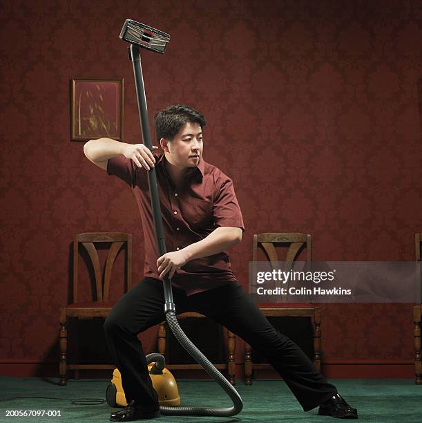 man doing kung fu pose with vacuum cleaner - sports man cave stock pictures, royalty-free photos & images