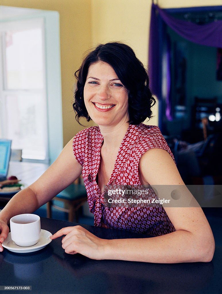 Woman sitting in coffee shop, smiling, portrait