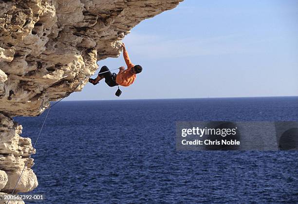 france, marseilles, les calanques, man climbing rock above sea - calanques stock pictures, royalty-free photos & images