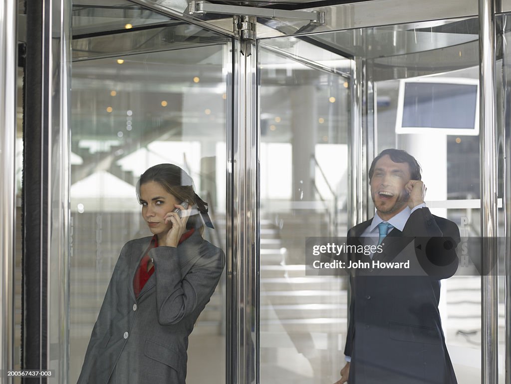 Businesspeople using mobile phone in revolving door