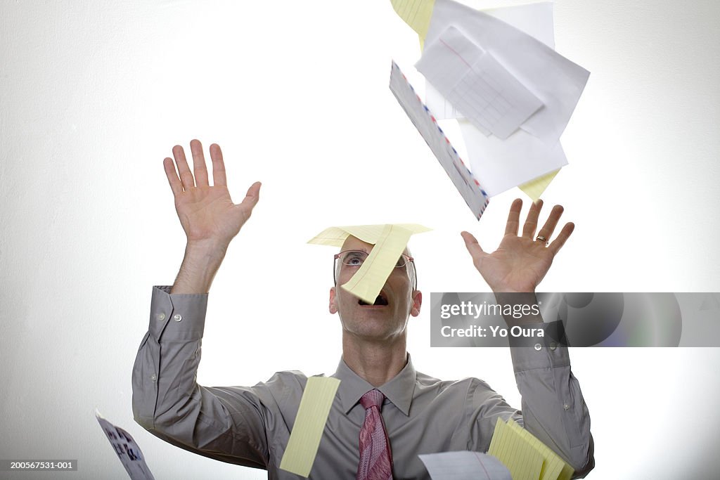 Business man shielding self from falling letters