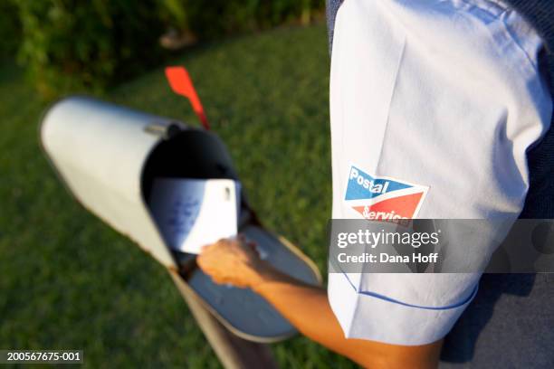 postal worker putting mail into mailbox, mid section, rear view - carteiro imagens e fotografias de stock