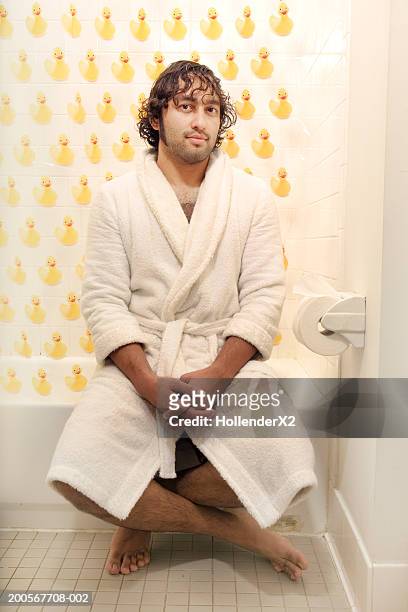 man in bathrobe sitting in bathroom in front of rubber duck curtain - robe stock pictures, royalty-free photos & images