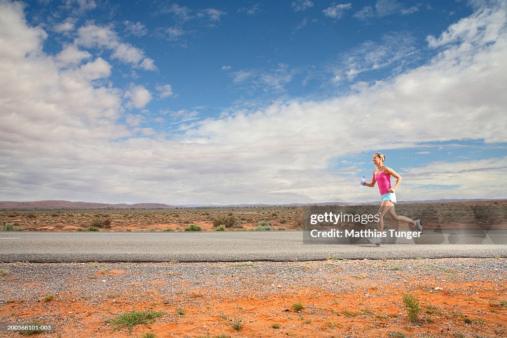 Woman running on desert road, side view