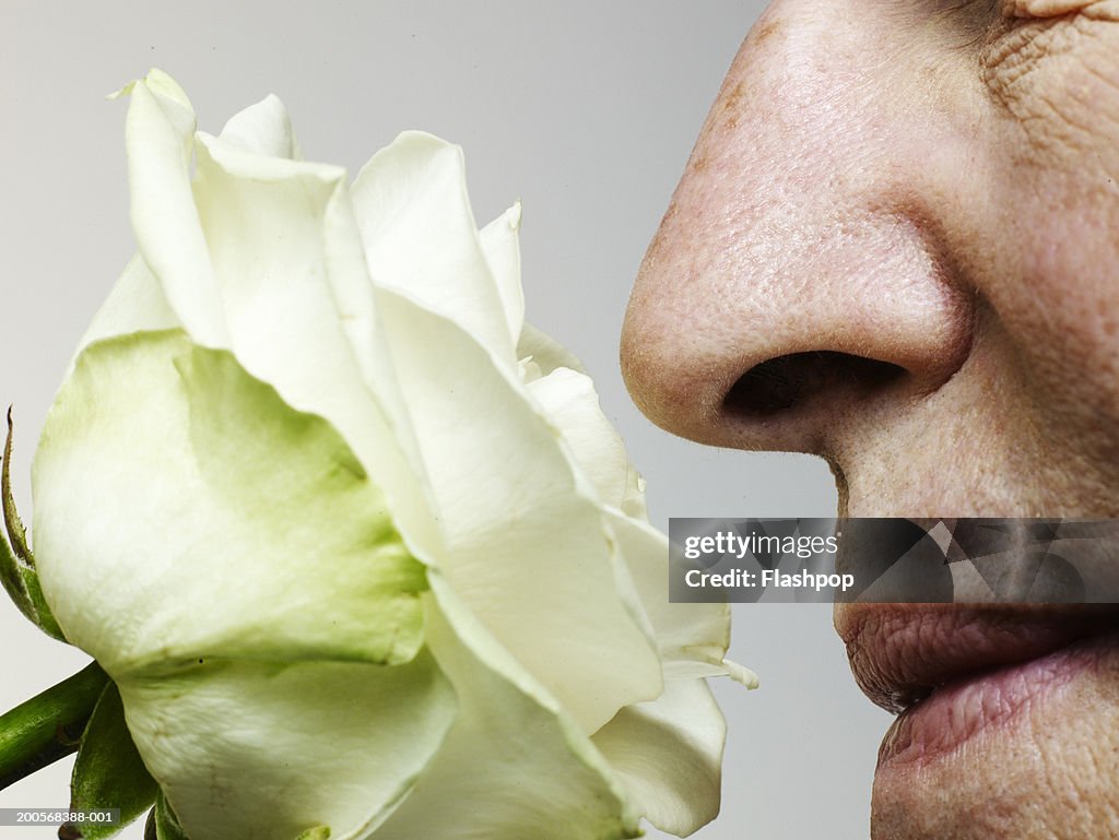 Senior man smelling rose, close-up