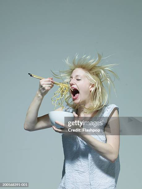 young woman eating noodles with chopsticks - woman fresh air photos et images de collection