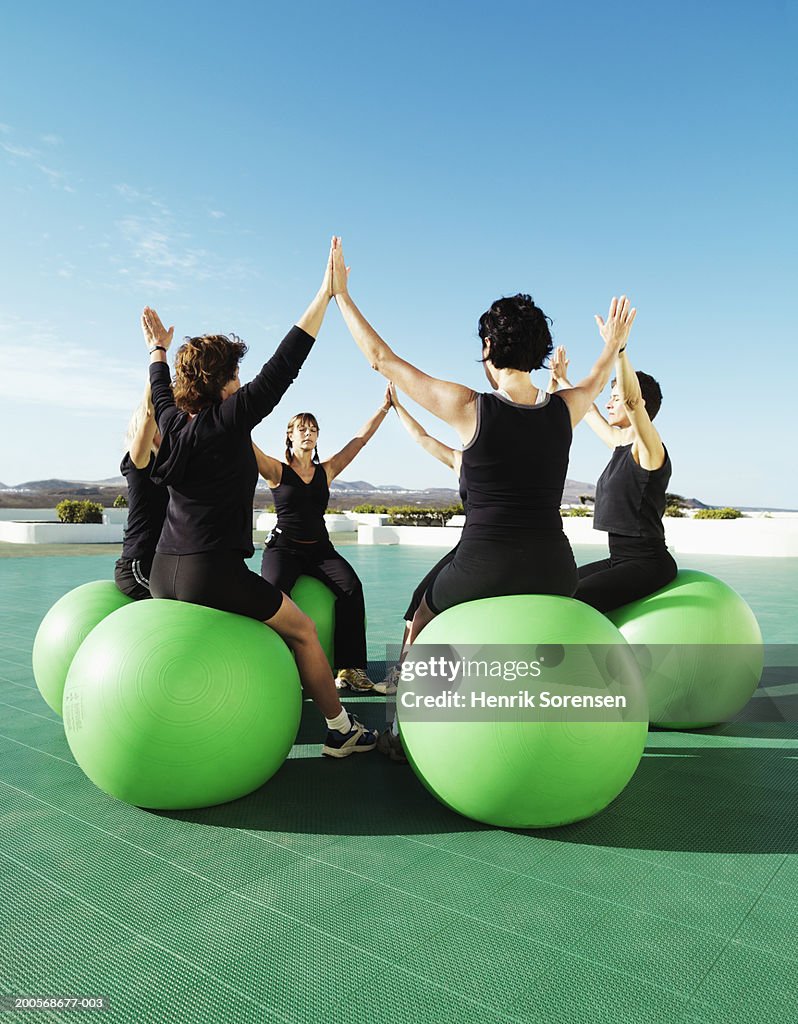 Group of women sitting on fitness balls, doing exercises