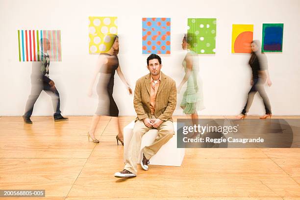 man sitting in art gallery, people walking in background - incidental people stock pictures, royalty-free photos & images