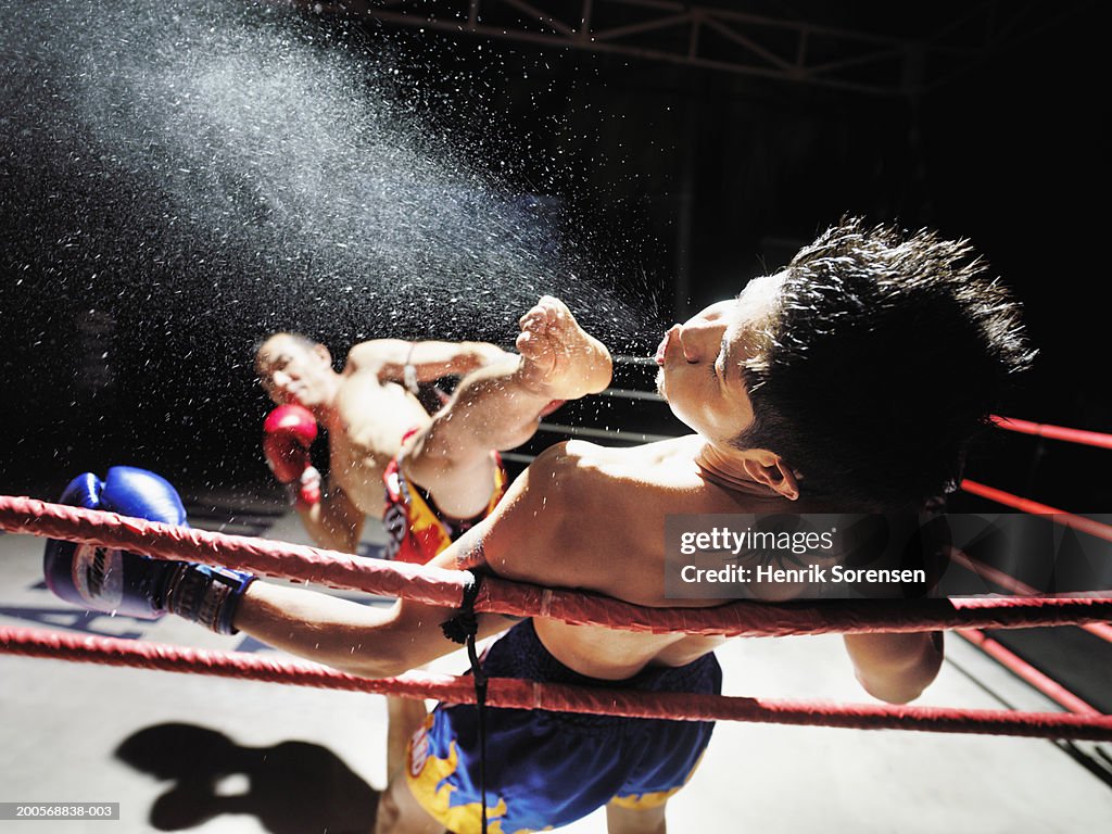 Thai boxing match, one boxer kicking another in face