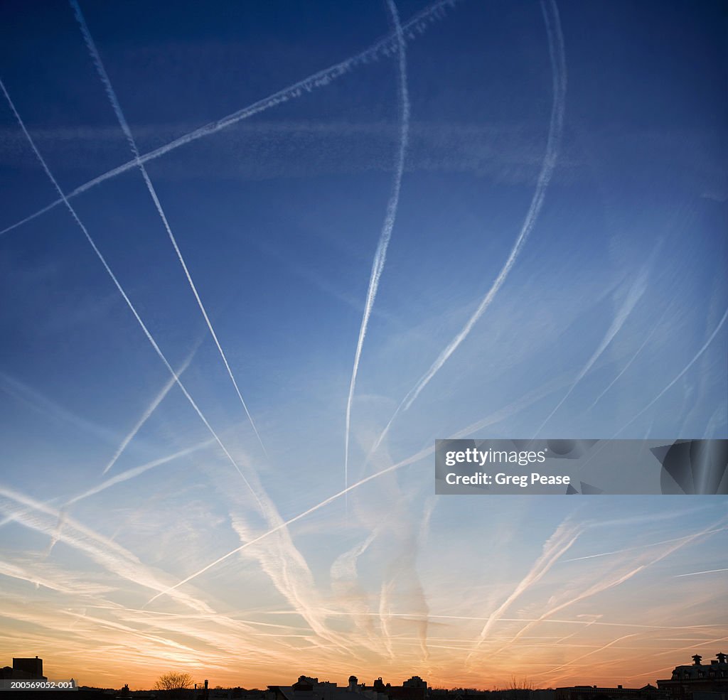 Jet vapour trails at sunset over rooftops