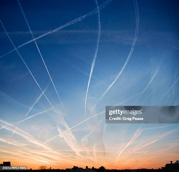 jet vapour trails at sunset over rooftops - sunset contrail stock pictures, royalty-free photos & images