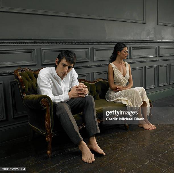 couple sitting on sofa, looking away - menselijke relaties stockfoto's en -beelden