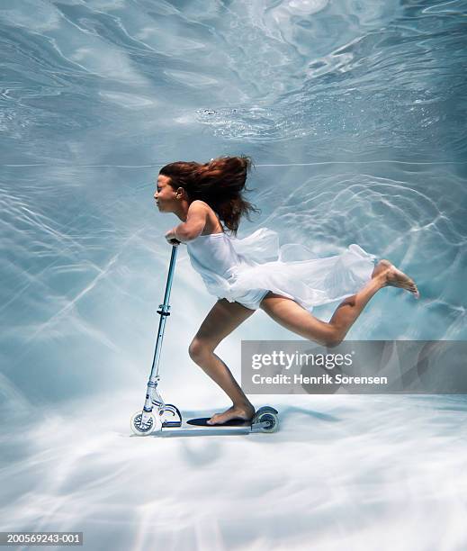 Girl (12-13) riding scooter underwater, side view