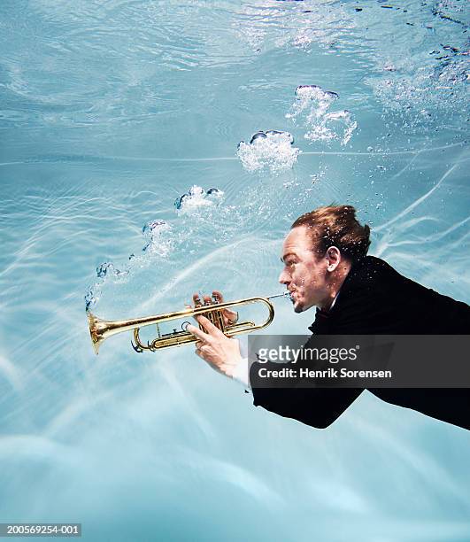 Man playing trumpet underwater, side view