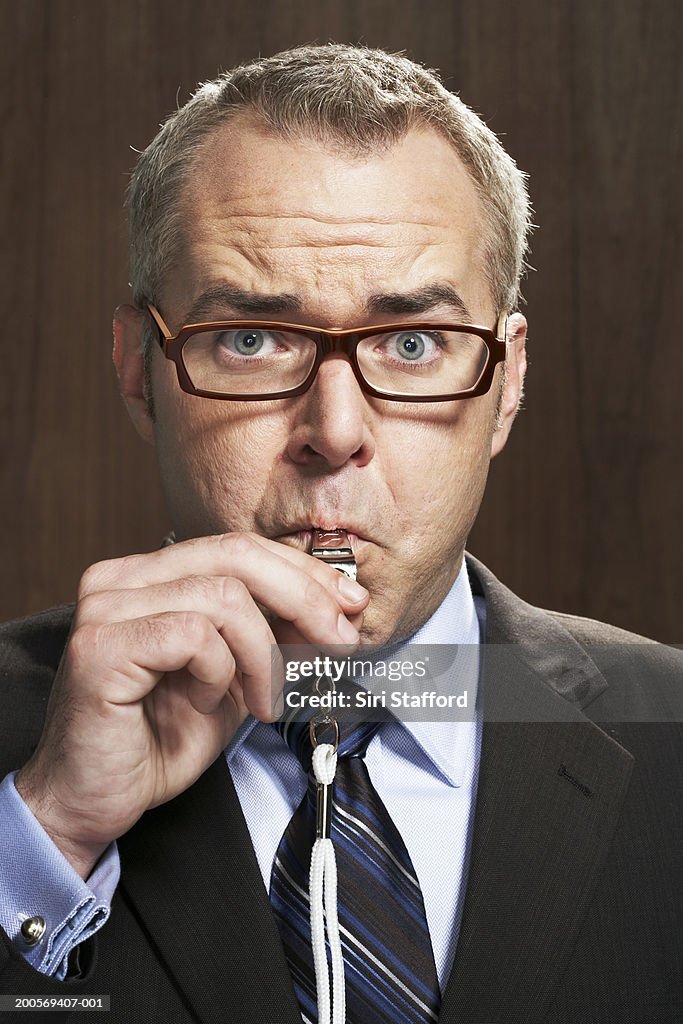 Business man blowing whistle