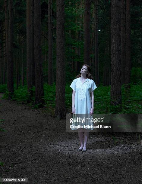 young woman standing in forest, looking up - camisa de noite imagens e fotografias de stock