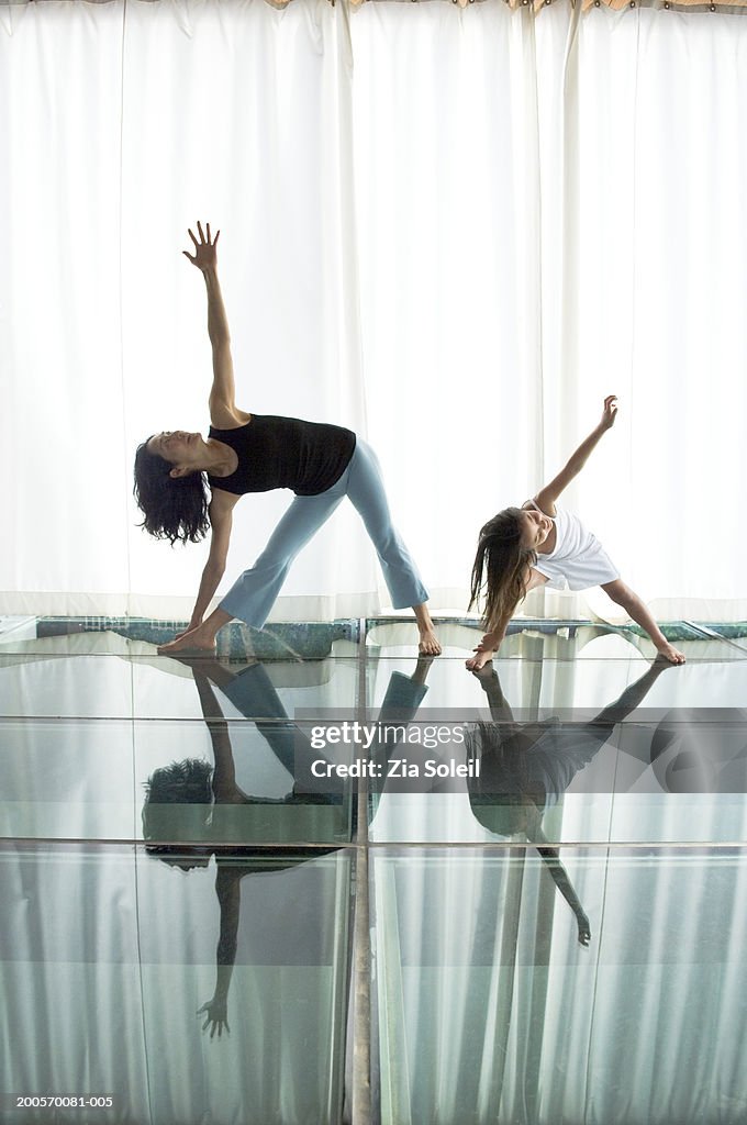 Mother with daughter (6-7) practising yoga