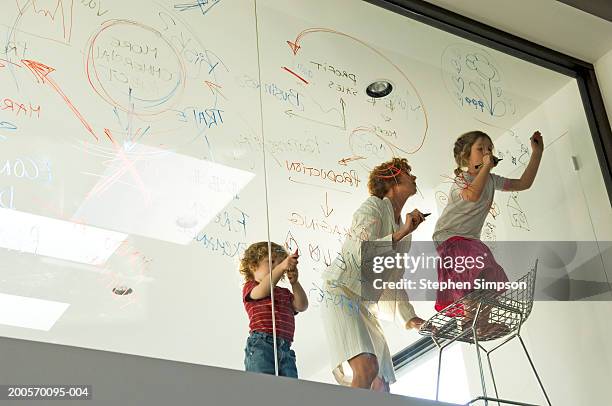 businesswoman with children (4-7) writing on glass - innocence project stock pictures, royalty-free photos & images