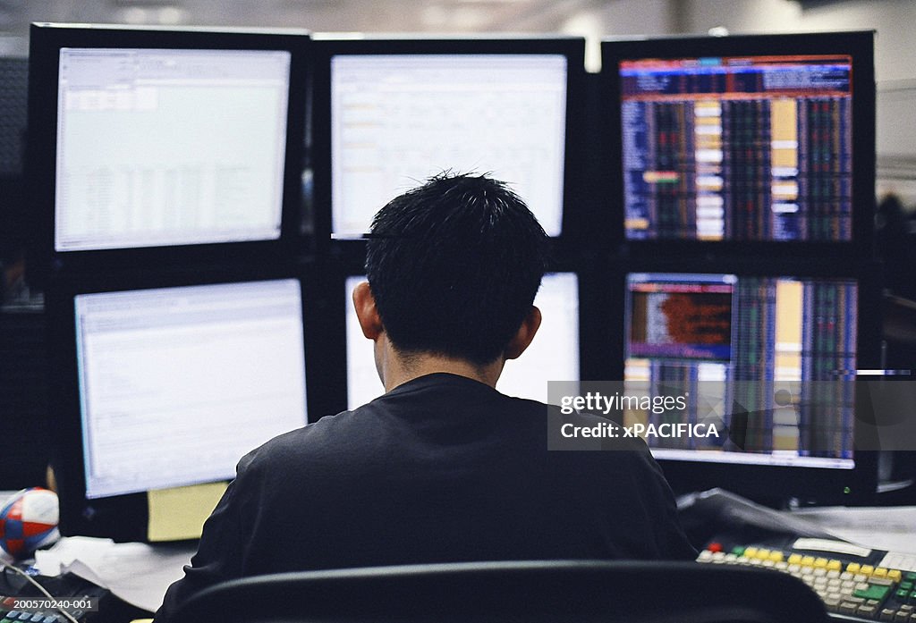 Businessman working desk with six monitors, rear view