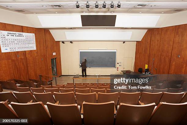professor writing on blackboard in empty classroom, elevated view - collegezaal stockfoto's en -beelden