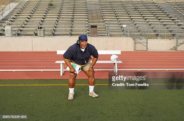 coach crouching on sidelines - american football coach stock-fotos und bilder