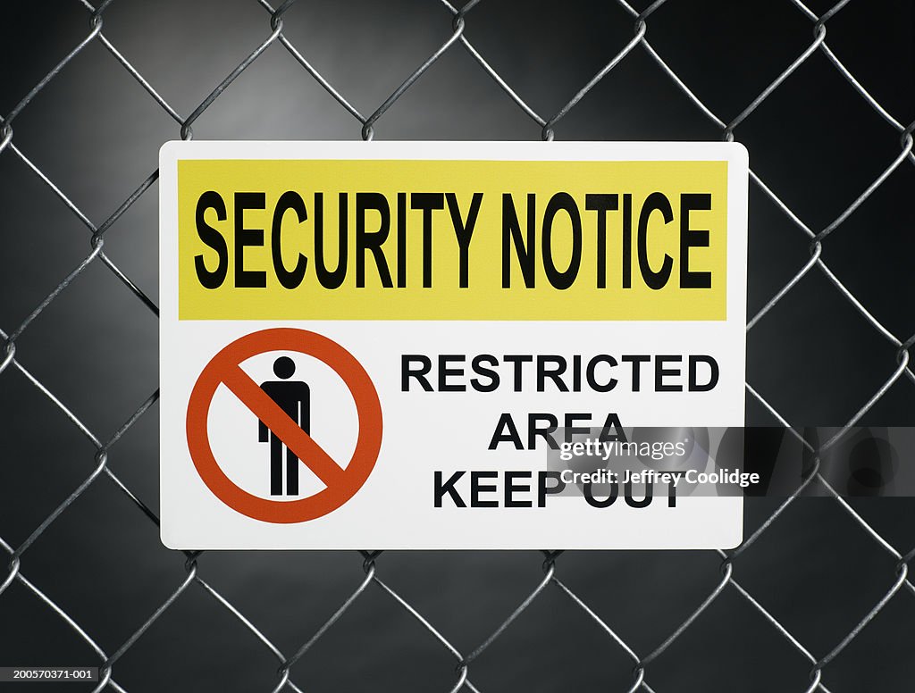 "Security notice, restricted area keep out" sign on fence 