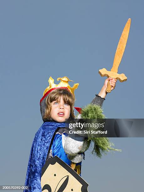 boy (4-5) in knight's costume riding stick horse, holding sword up - ritter stock-fotos und bilder