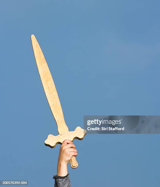 boy (4-5) holding wooden sword against sky, close-up of hand - sword stock pictures, royalty-free photos & images